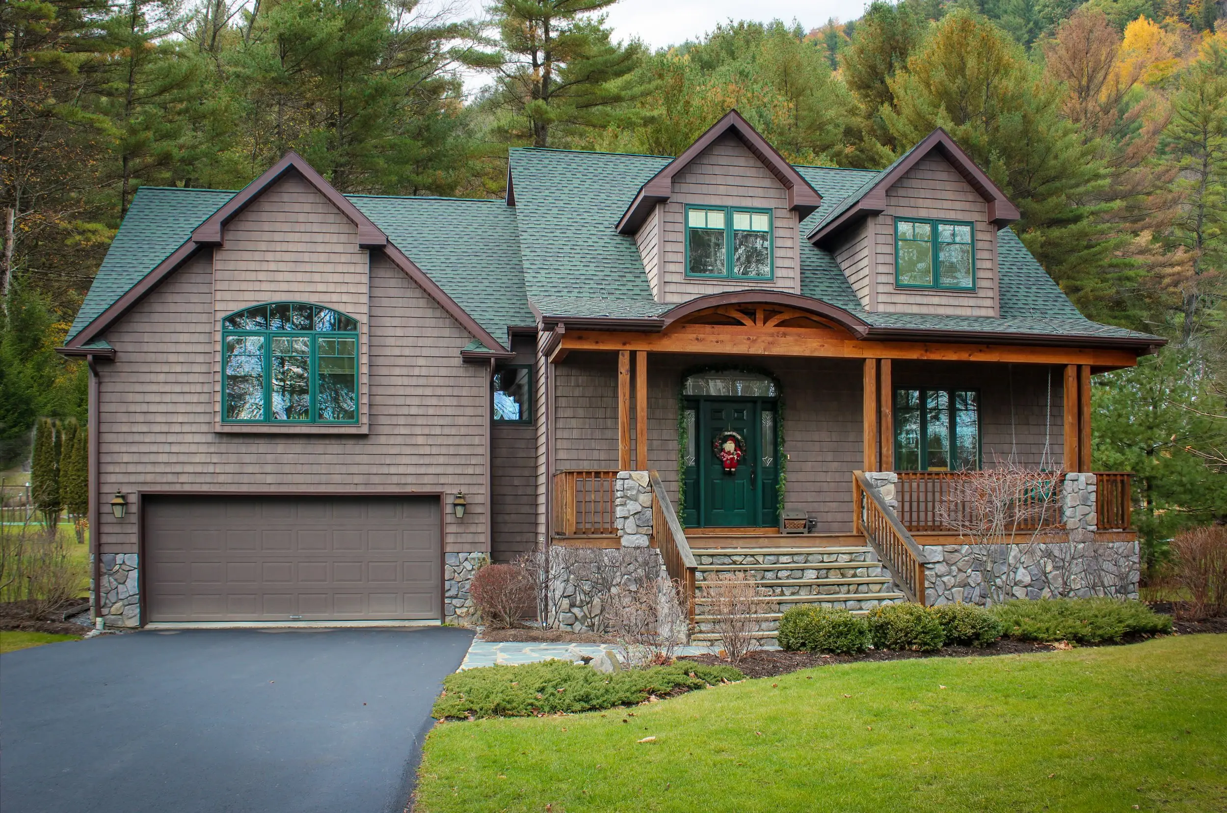 Cape Cod-style home with cedar shingles, a green roof and a covered stone porch