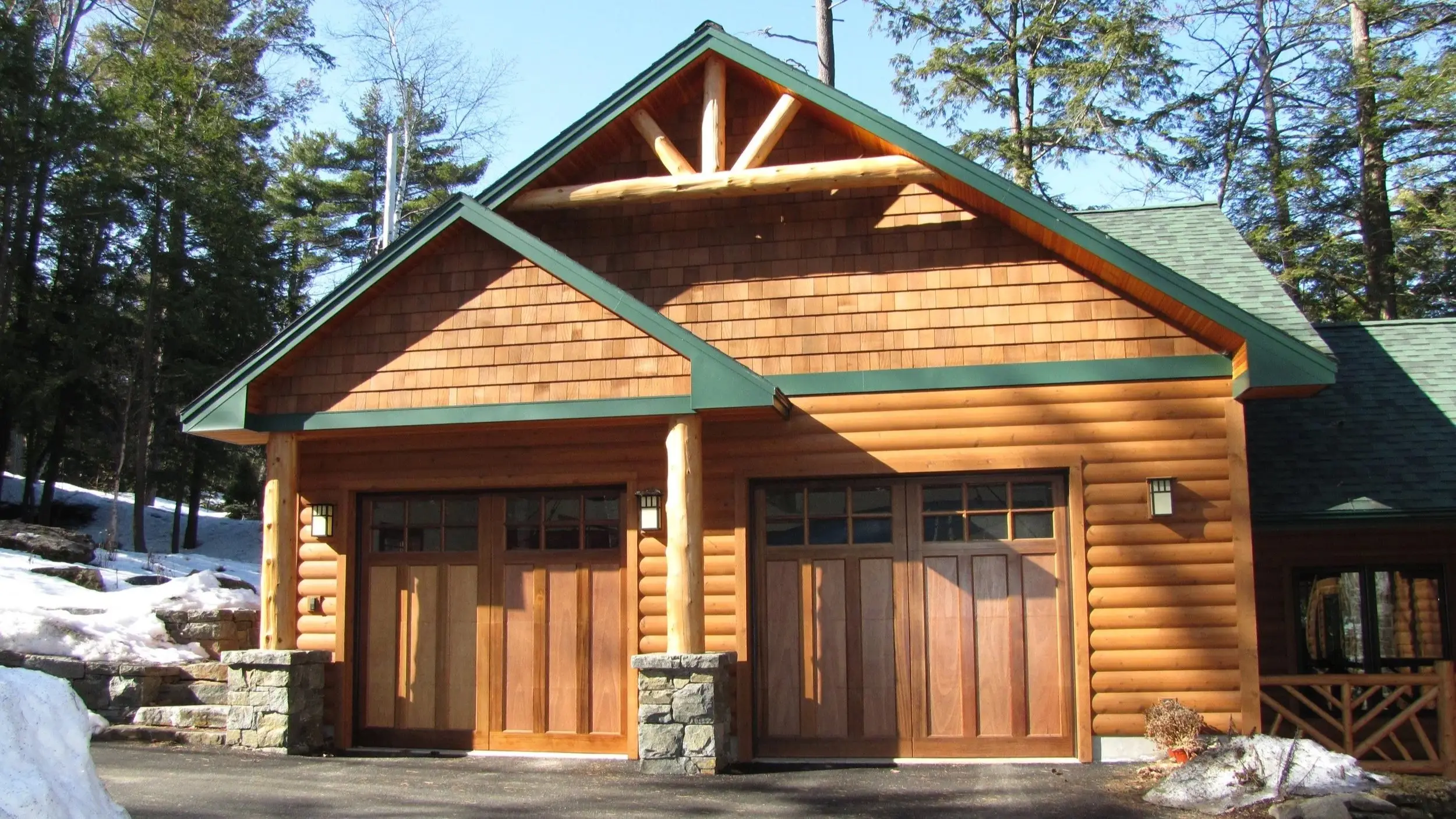 Log garage with a cedar-shingled gable and two wood carriage doors