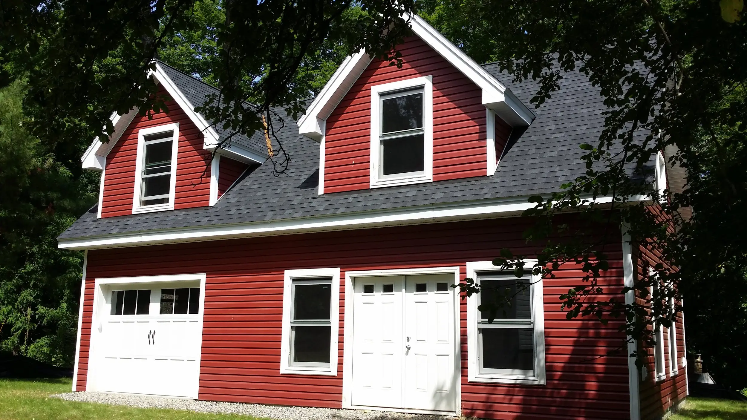 Red two-car garage with white carriage doors and dormers above