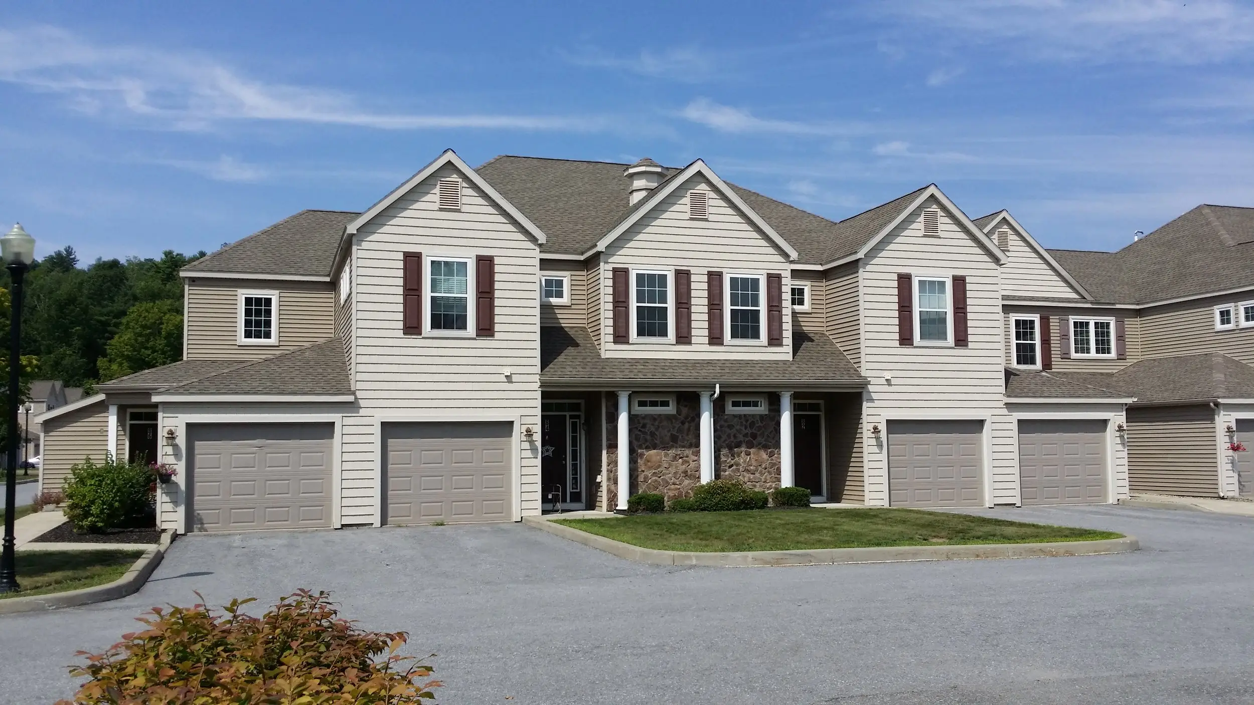 Townhouses with burgundy shutters and single garages around a stone-faced entry