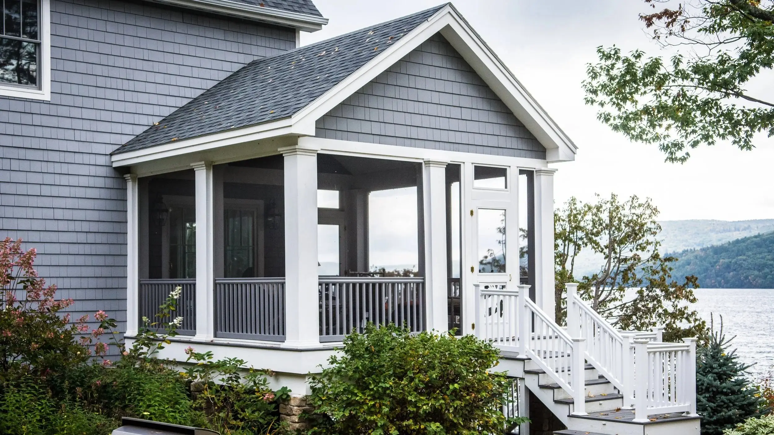 Screened porch with white railings overlooking a lake