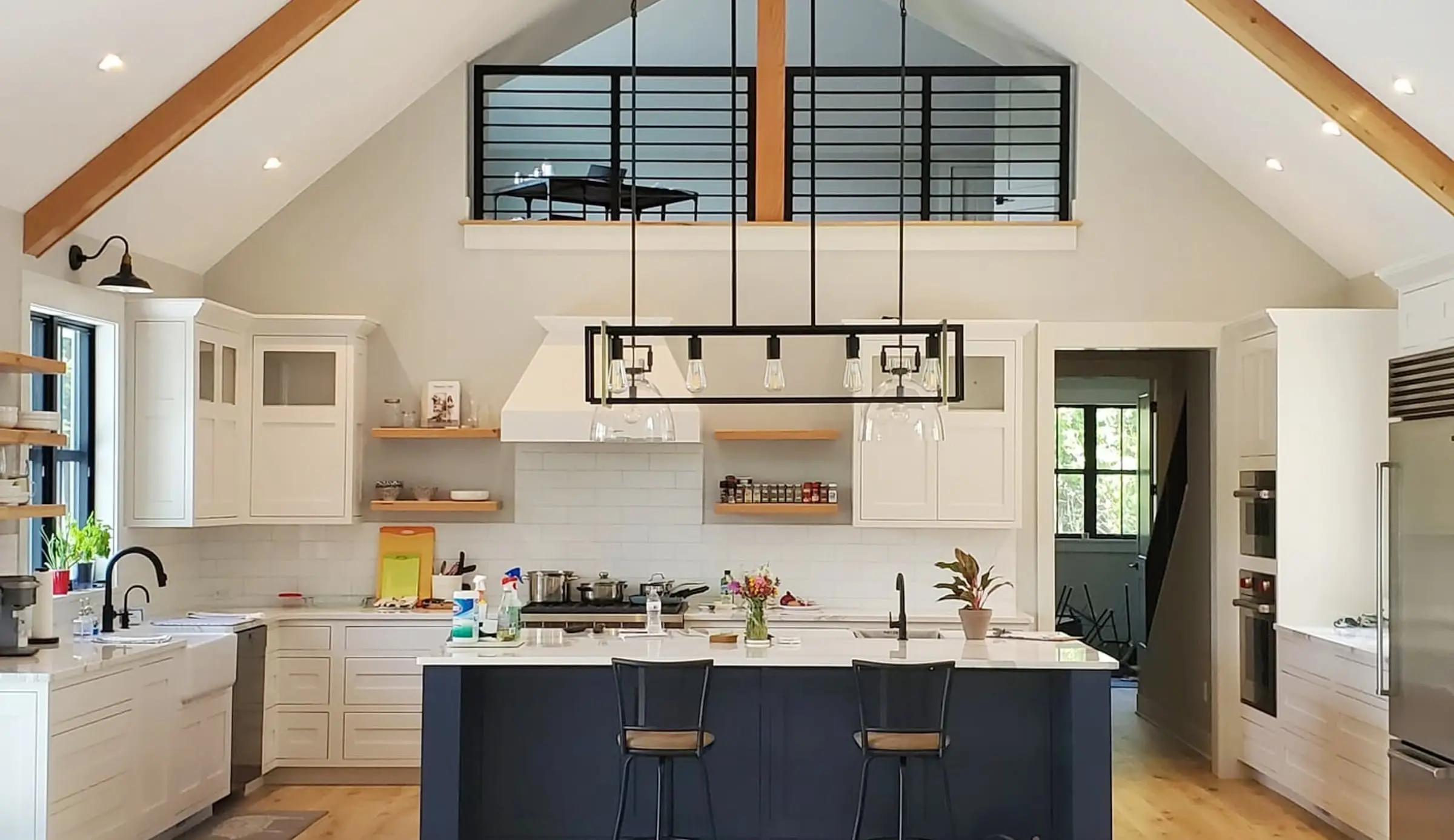 Vaulted kitchen with exposed timber trusses and a loft balcony above